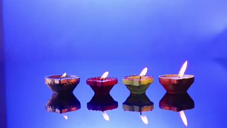 close up of burning candles in row celebrating diwali on blue background, with copy space