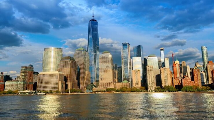 Horizonte de Lower Manhattan e One World Trade Center vistos da água. Vista ampla dos arranha-céus de Nova York sob um céu azul nublado a partir do Rio Hudson.