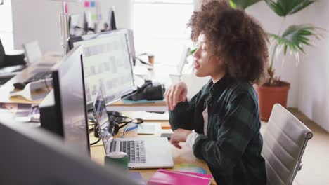 Mixed-race-woman-tapping-on-computer-in-creative-office