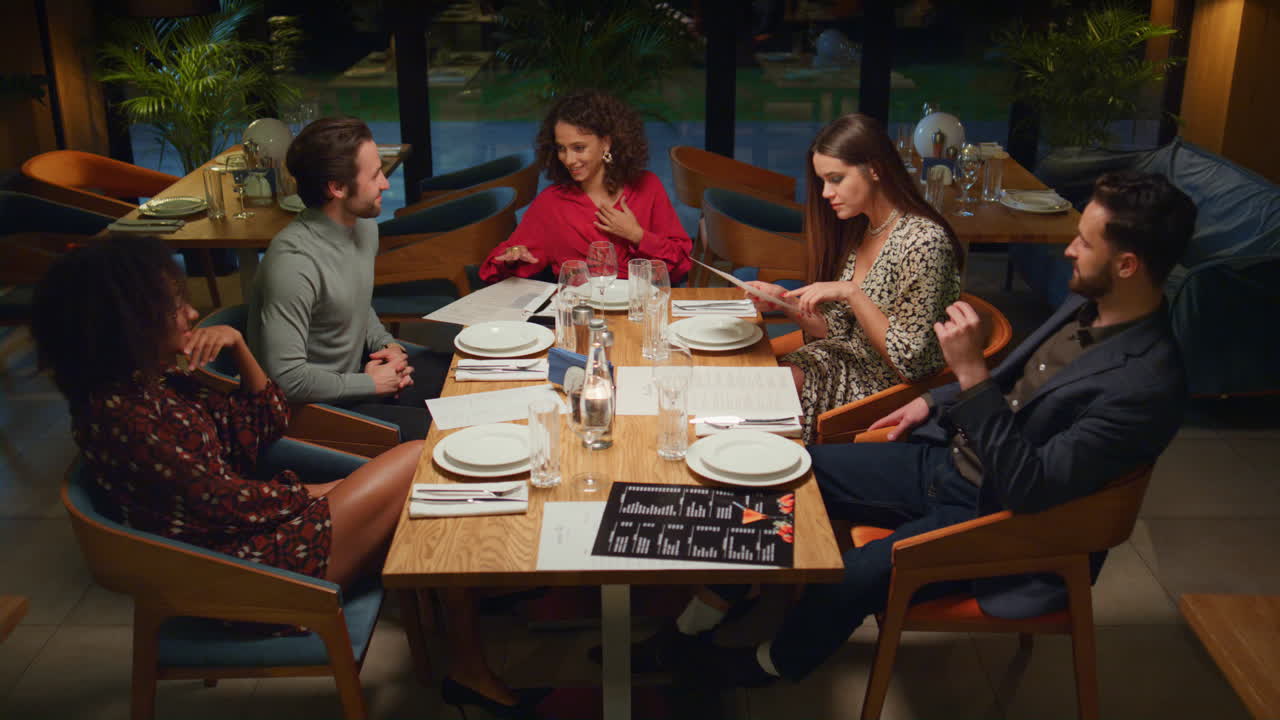 Diverse friends talking together on fancy restaurant meeting at cozy evening.
