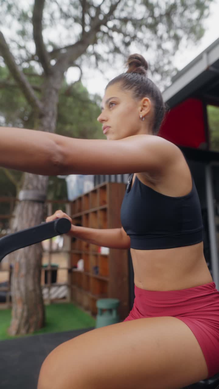 Woman trains on an exercise machine at an outdoor gym