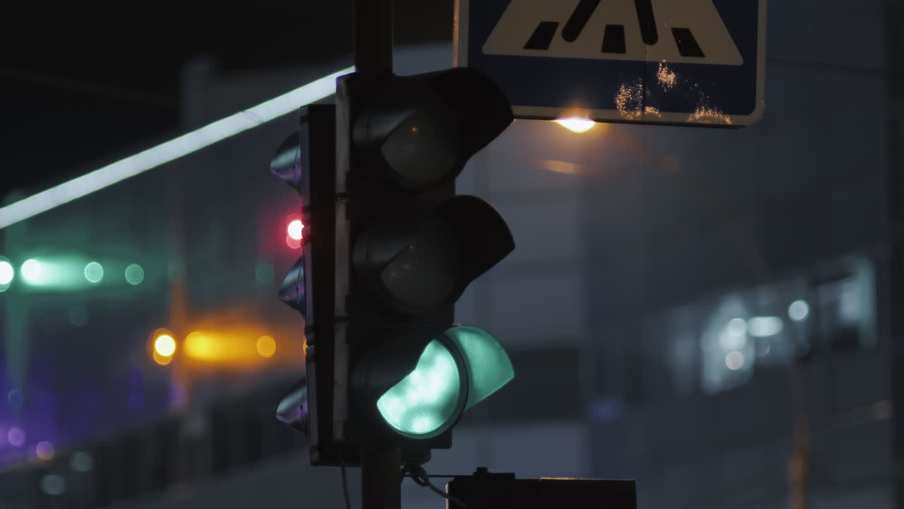 A traffic light is lit in green against the backdrop of a modern building. Evening city