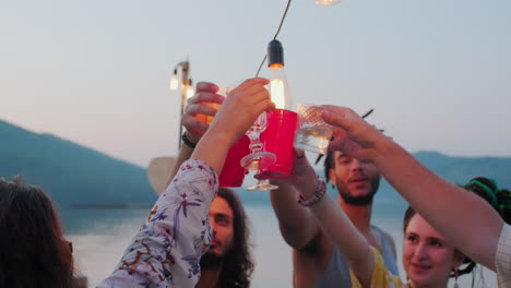 happy young friends drinking and dancing at lake party