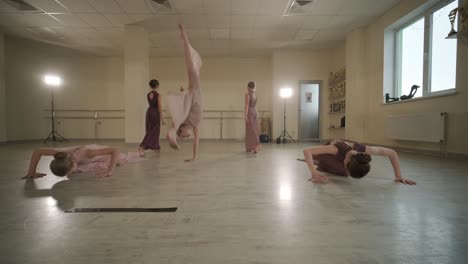 un grupo de jóvenes estudiantes de ballet con ropa de baile negra practicando posiciones en un amplio estudio de ballet con pisos de madera y barras montadas en la pared. expresiones enfocadas y movimientos sincronizados.