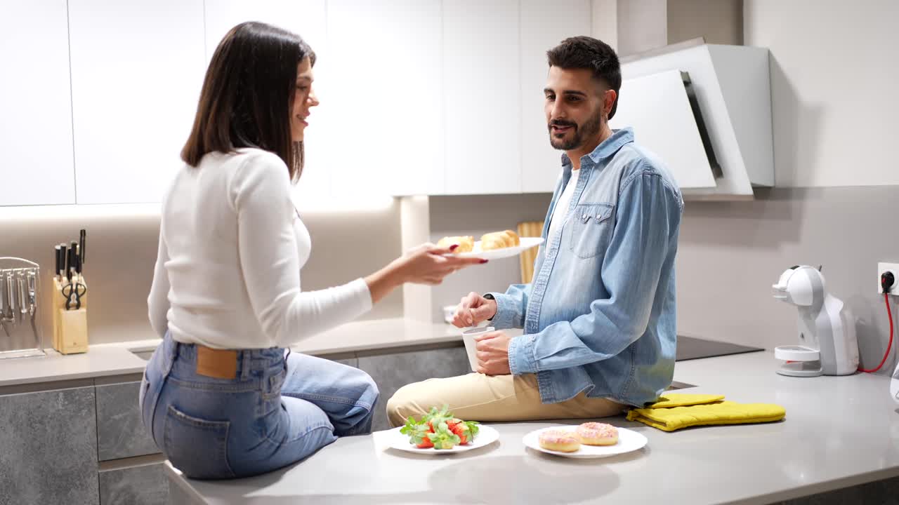Casal aproveitando o café da manhã junto em cozinha moderna