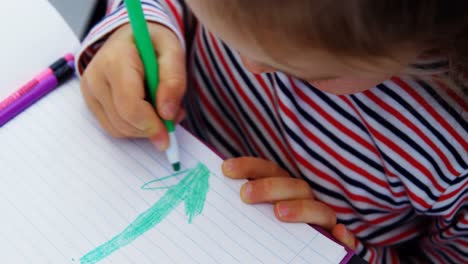 cute schoolgirl drawing pictures in classroom