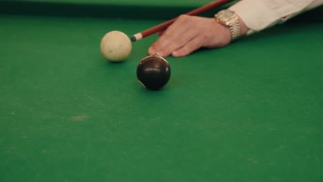 player prepares slow motion billiards shot with black ball on green table