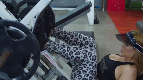 una mujer joven usa una máquina de prensa de piernas en ropa deportiva en un gimnasio del caribe