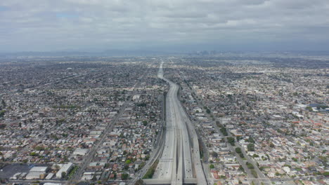 AERIAL:-Spectacular-View-over-Endless-City-Los-Angeles,-California-with-Big-Highway-Connecting-to-Downtown-on-Cloudy-Overcast-Day