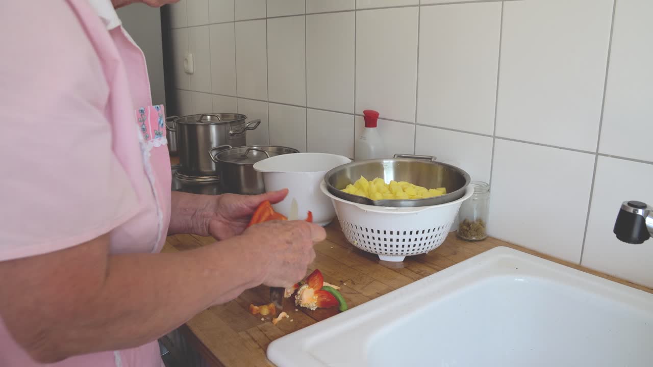 anciana cocinando en casa, lavando y limpiando paprika en el fregadero de la cocina