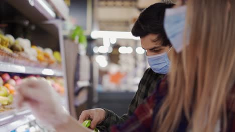 Young-couple-in-face-masks-shopping-for-fresh-produce-at-market