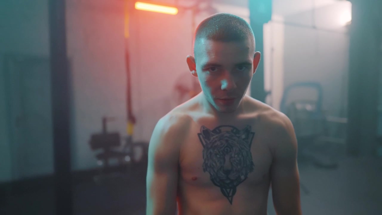 Ritratto di un uomo determinato e tatuato in un'ambientazione drammatica in palestra