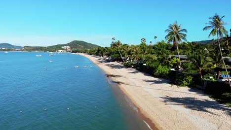 Dolly-Aéreo-A-La-Vista-De-La-Gente-En-Una-Playa-Tropical-De-Arena-Junto-A-Un-Resort-De-Lujo-En-Tailandia