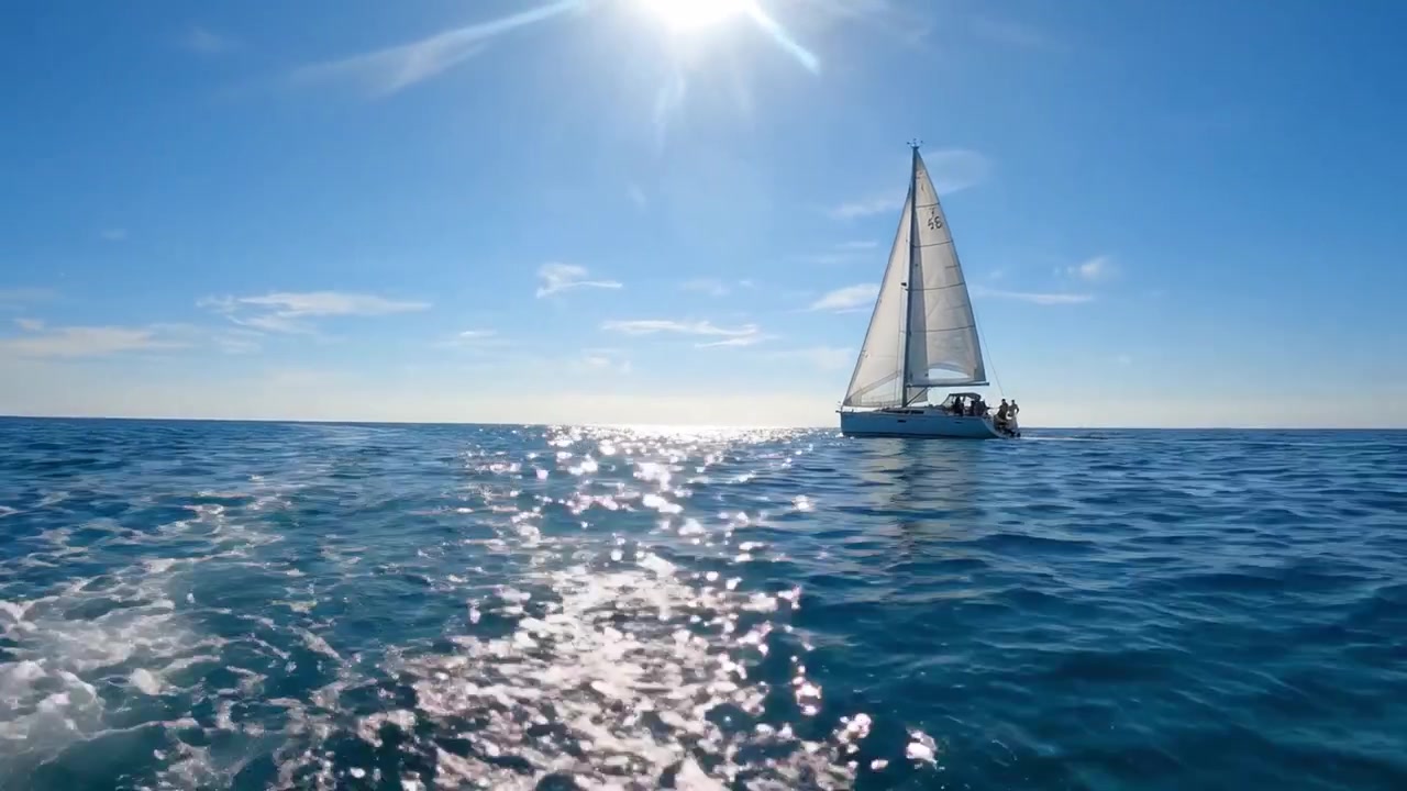 A Tranquil Sailing Adventure Over Crystal Clear Waters Beneath a Bright Sunlit Sky, Perfect for Enjoying the Serenity of the Open Sea and Scenic Views.