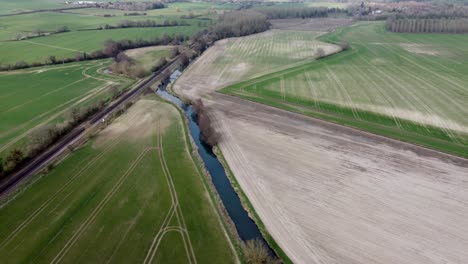 Vista-Aérea-De-Un-Río-Y-Una-Vía-Férrea-Con-Campos-Verdes