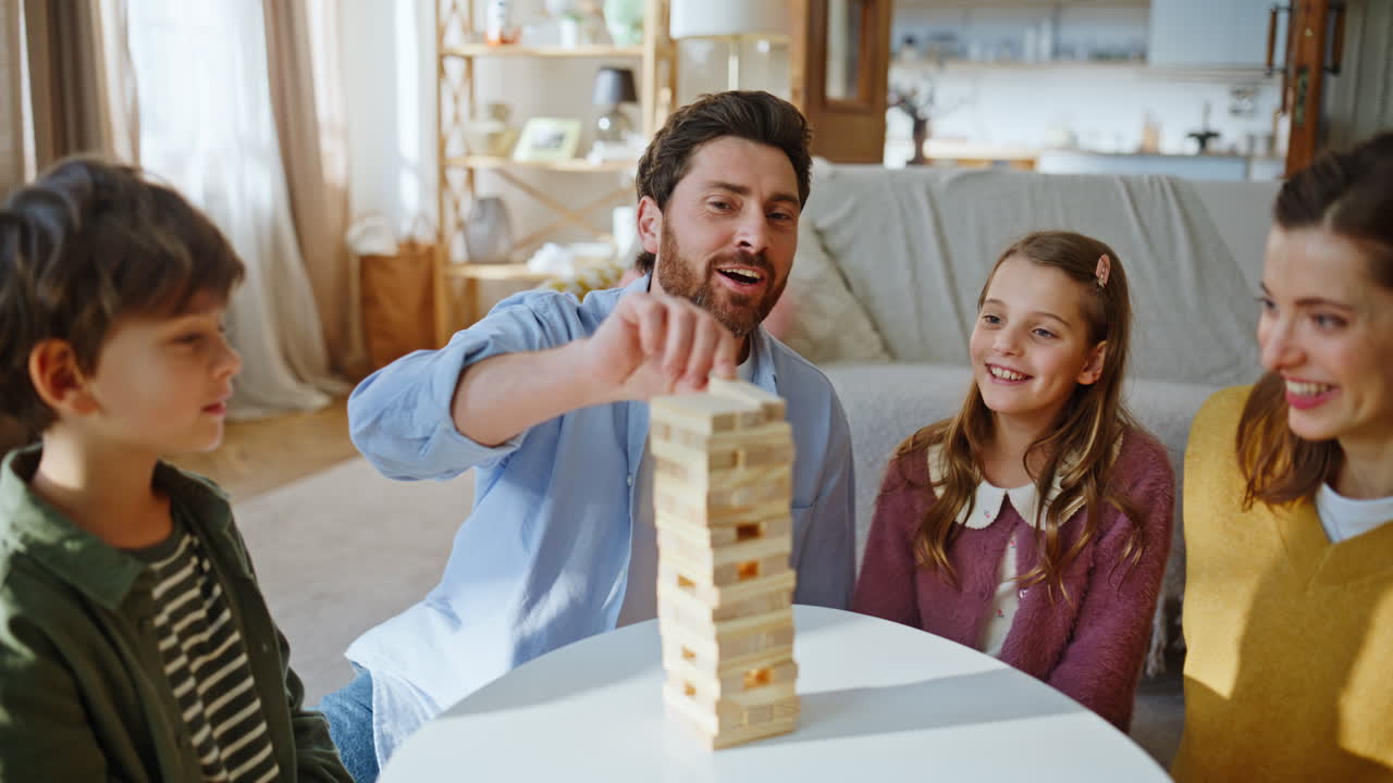 Famiglia che gioca a un gioco da tavolo nel fine settimana in un appartamento, primo piano. Parenti che costruiscono una torre