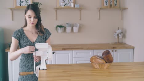 happy woman connects handle to home flour grinder in kitchen