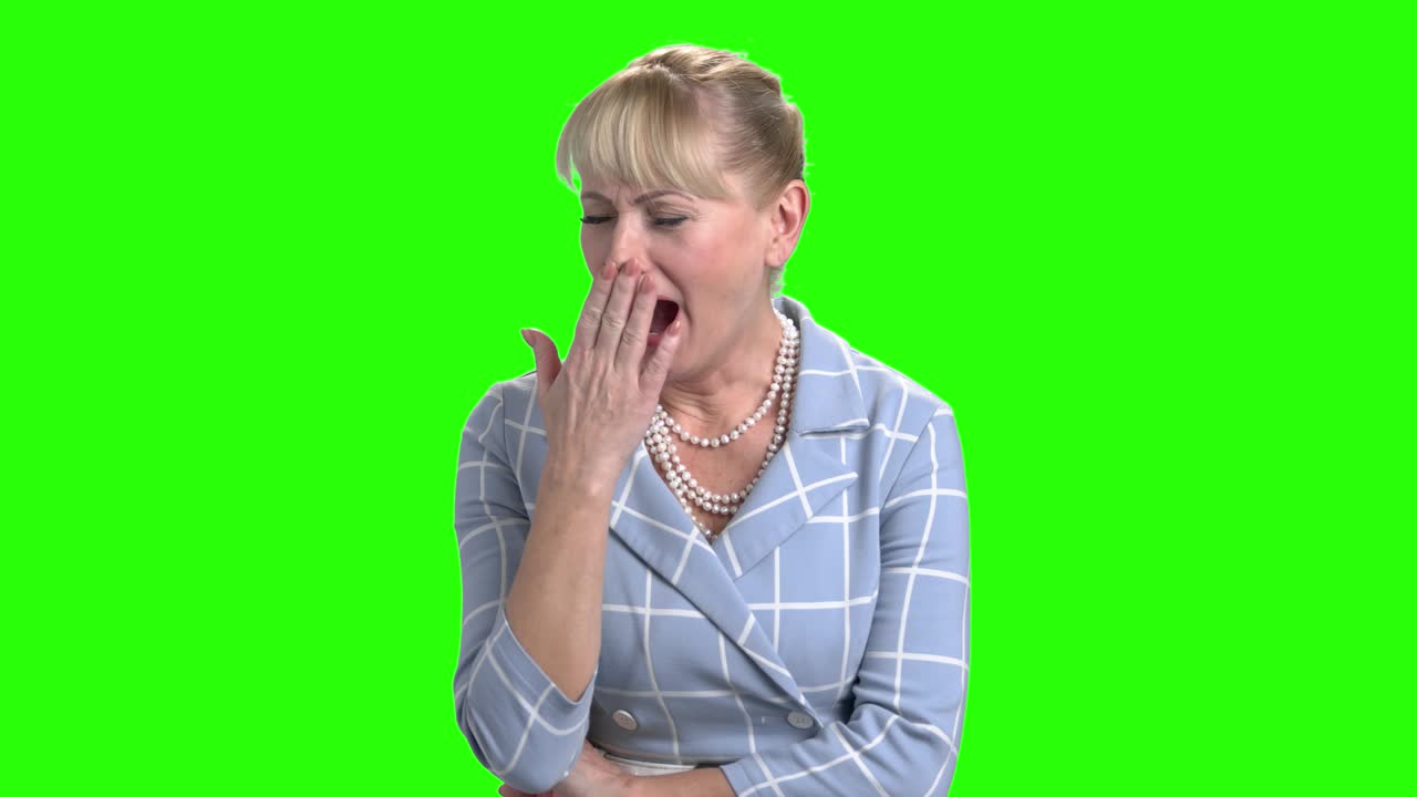 la mujer madura está bostezando en el fondo de chroma key.