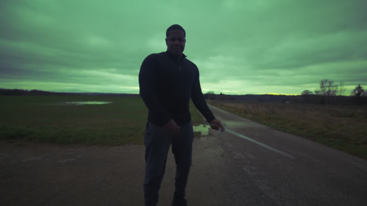 현대의 검은 검사 전사는 녹색 하늘 아래 열린 필드에서 대결 상대를 기다리고 있습니다. - 유럽, 4k - 근육, 협박, 그림자, 형상, 흐릿한, 어두운 옷, 강력한, 절단에 대한 입장을 조정합니다.