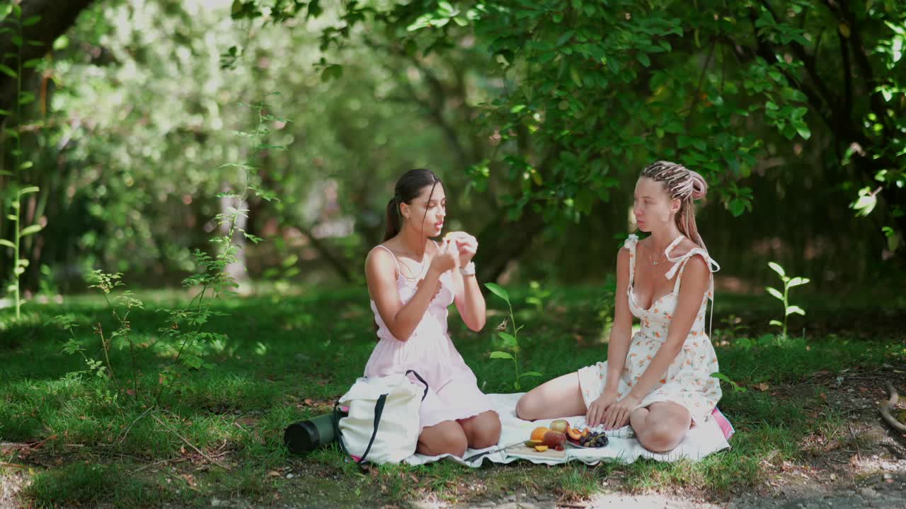 두 명의 젊은 여성들이 공원에서 피크닉을 즐기고 있습니다.