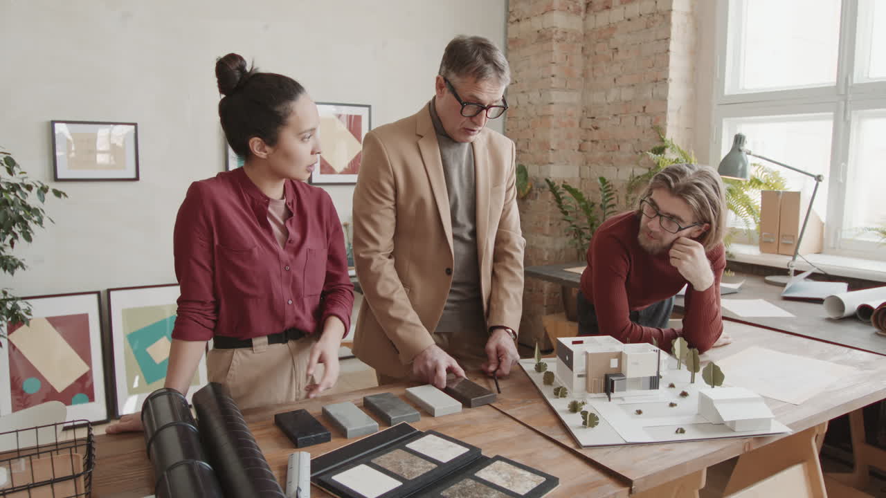 Team Of Architects With House Layout Choosing Building Material