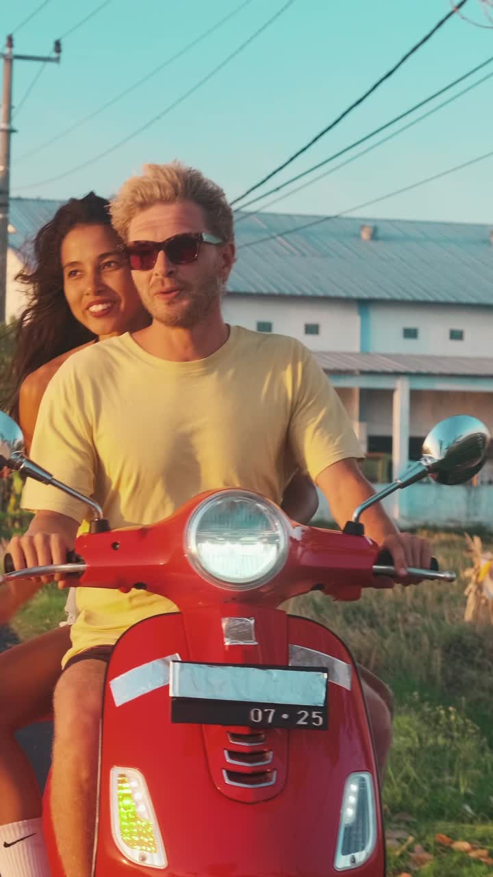 Couple riding red scooter in asia during sunset