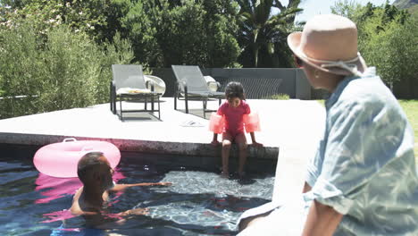 biracial family enjoys a sunny day by the pool, with a child ready to jump in