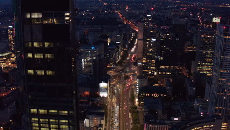 Tilt-down-shot-heavy-traffic-in-wide-multilane-street.-Aerial-view-of-downtown-at-night.-Warsaw,-Poland