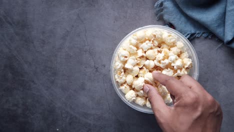 hand reaching into a bowl of popcorn