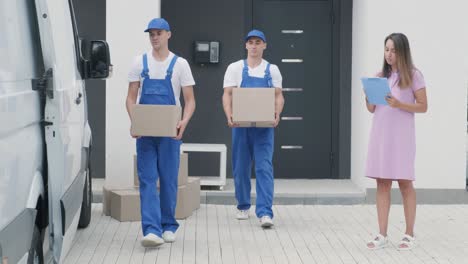 two young workers of removal company are loading boxes and furniture into a minibus