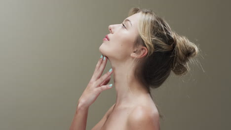 portrait of caucasian woman with hair up touching her chin, copy space, slow motion