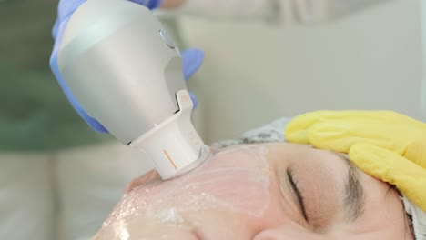 professional face skin rejuvenation, lifting procedure. cosmetologist uses modern ultrasound device. hardware cosmetology