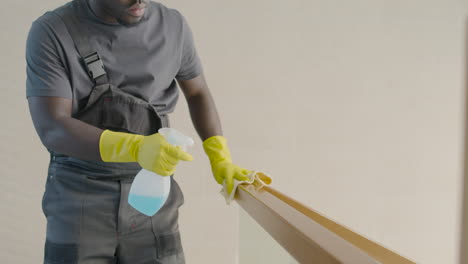 close up view of cleaning man wearing gloves cleaning stair railing inside an office building