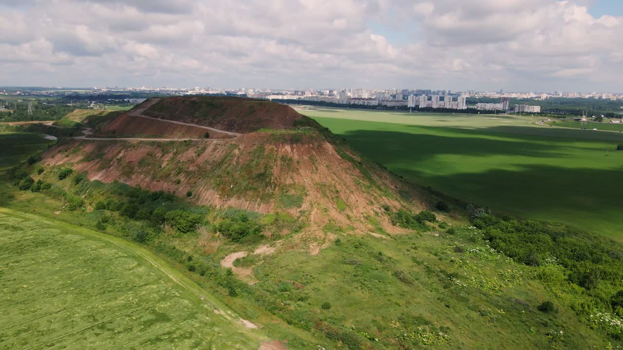 Household waste landfill. Closed for processing. Environment protection. Close-up shot. The city is visible on the horizon. Aerial photography.