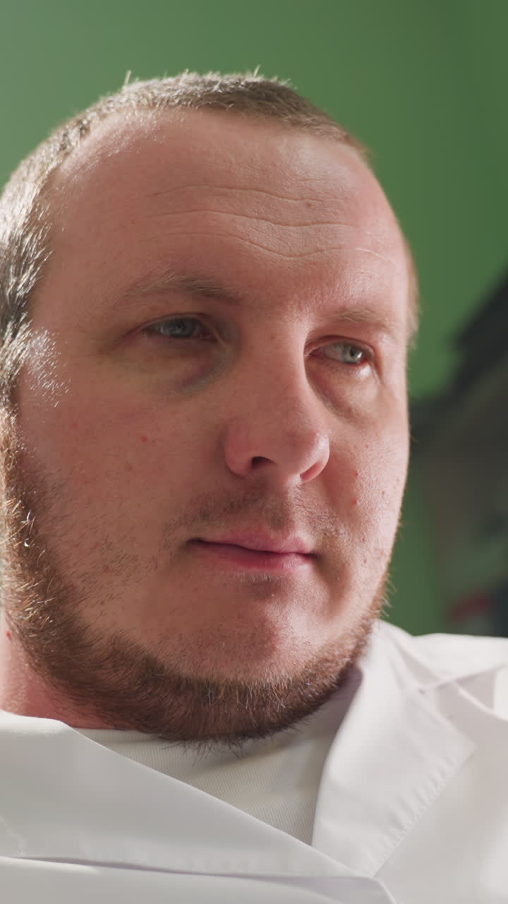 A close-up view of a technician in a lab coat, deep in thought while sitting in a laboratory environment