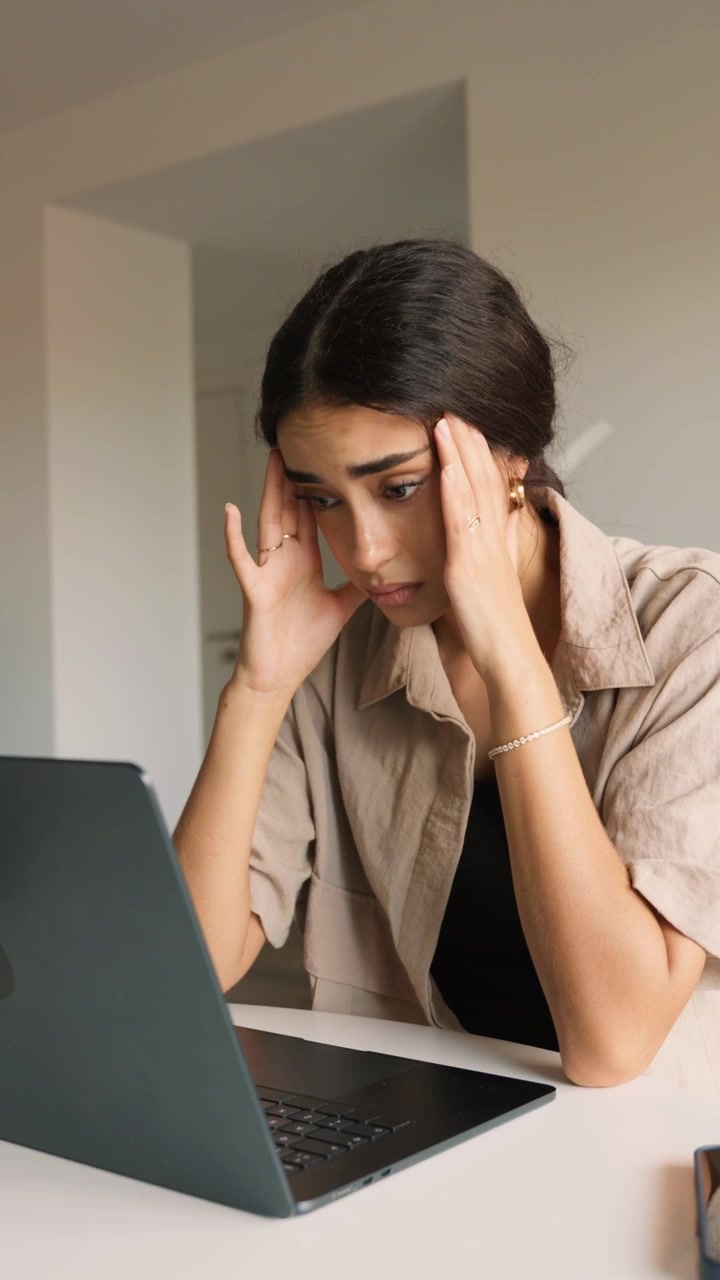 Giovane donna stressata che lavora al portatile a casa
