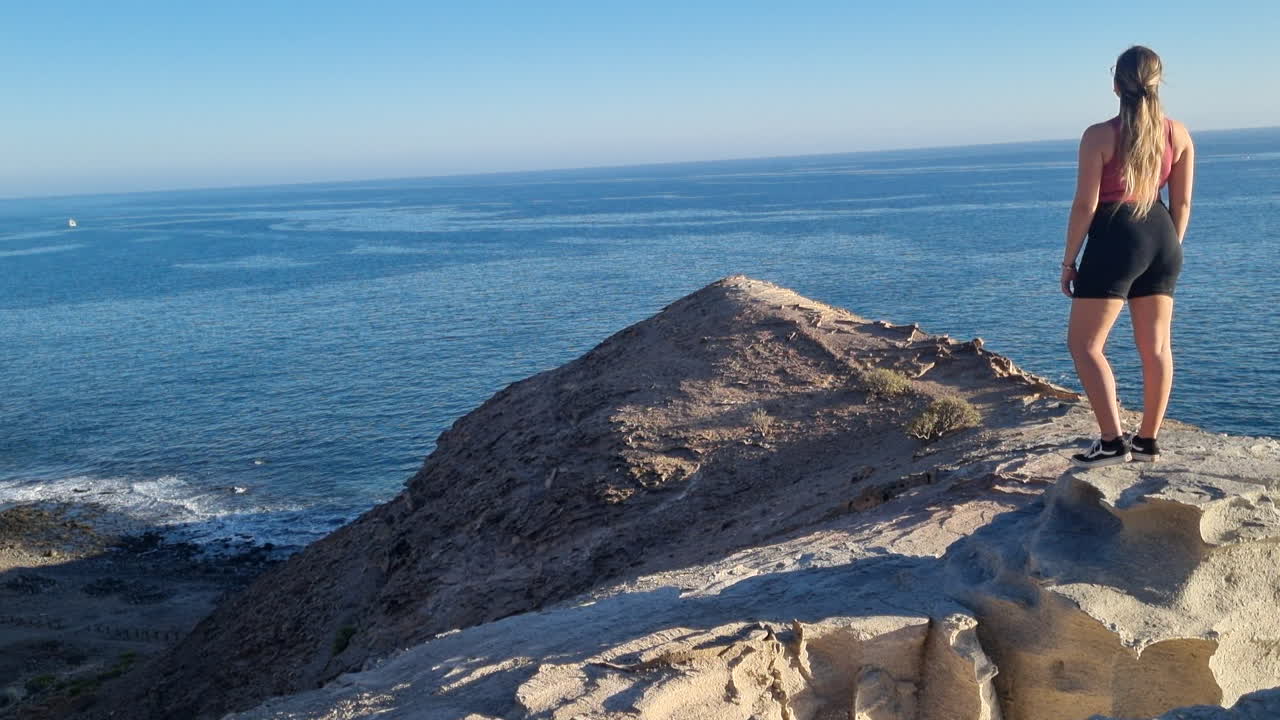 mujer joven observa las maravillosas vistas ubicadas cerca de la playa de medio almud en la isla de gran canaria, municipio de mogán