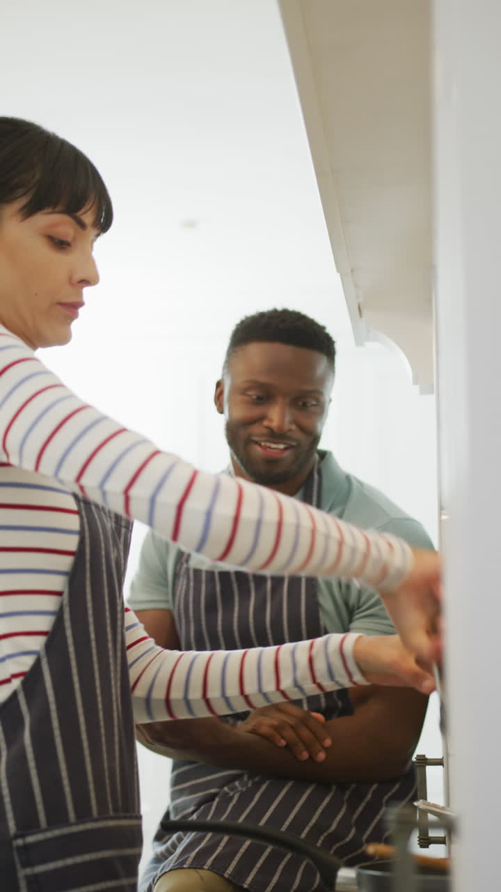 Vertical video of happy diverse couple cooking at home