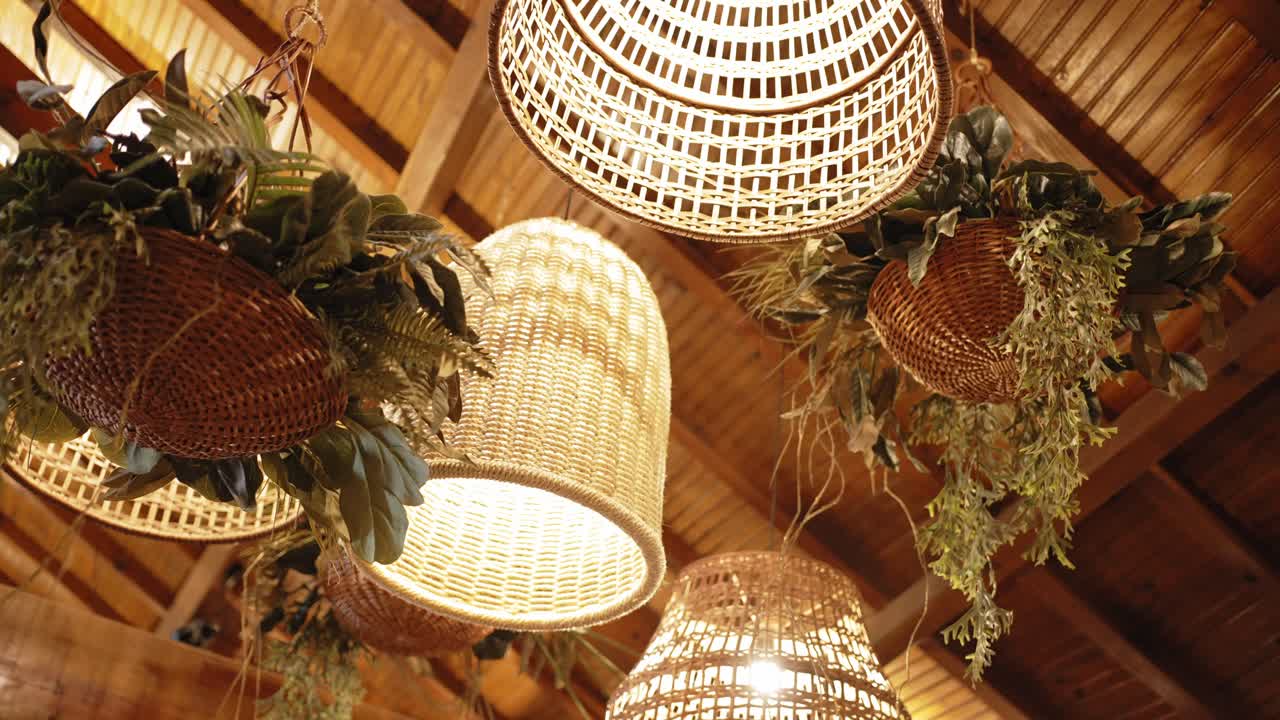 Wicker lanterns and hanging greenery create warm rustic decor for indoor wedding venue