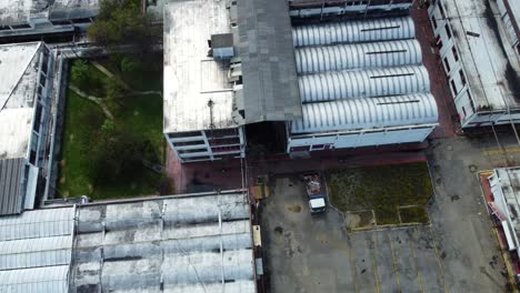 surrounding the factory, a patchwork of warehouses and factories sprawls outwards, their corrugated metal roofs glinting in the sunlight