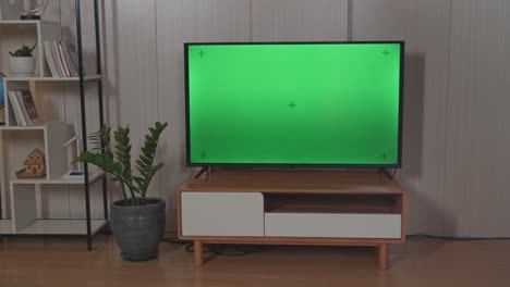 male hand with tv remote pressing button and changing, switch channels. watches green mock-up screen tv