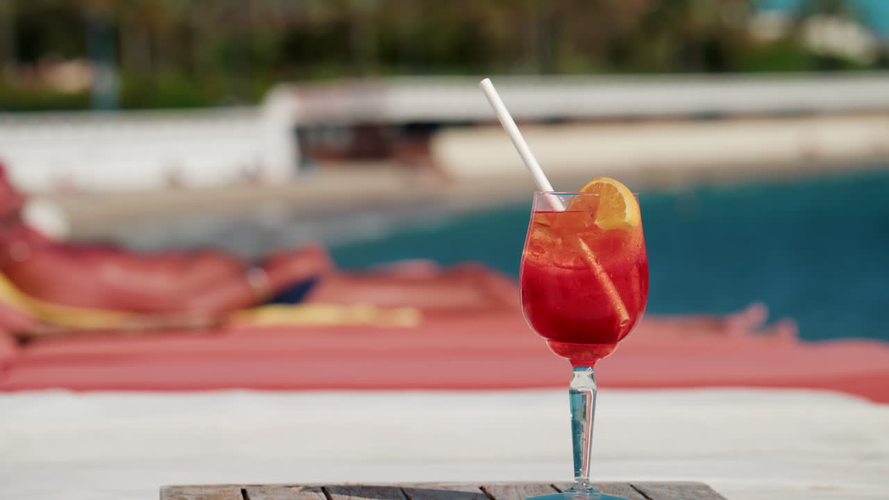 Primo piano di un cocktail rosso-arancio rinfrescante con una fetta d'arancia e cubetti di ghiaccio, scattato all'aperto in una giornata di sole a Cannes