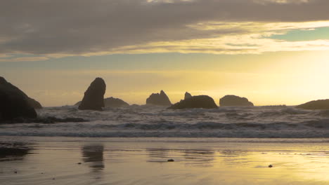 Olas-En-Cámara-Lenta-Llegando-A-Tierra-Durante-Una-Hermosa-Puesta-De-Sol-En-La-Costa-De-Oregon-En-Bandon,-Parque-Estatal-Face-Rock-Beach