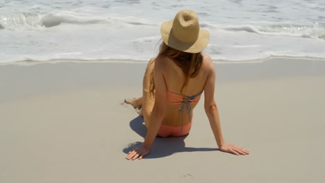 vista trasera de una mujer caucásica relajándose en la playa 4k