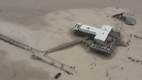 Drone---Toma-Aérea-Superior-De-Un-Restaurante,-Edificio-Con-La-Playa-De-Arena-Con-Turistas-Y-Gente-En-St