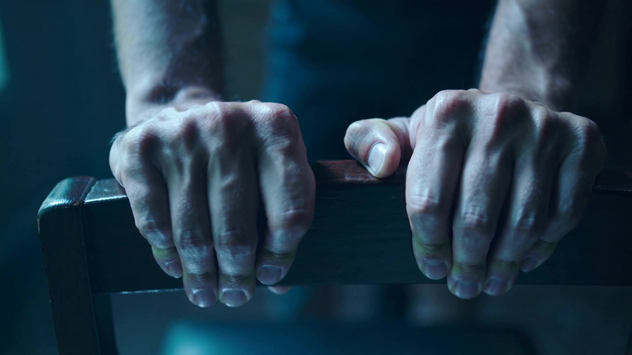 Gripping hands, forearms tightening on wood chair rail after placing under left light in dark top