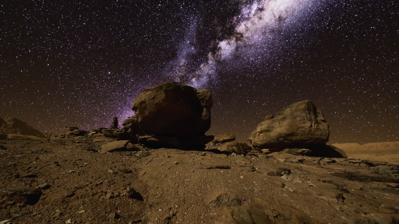 cielo nocturno estrellado sobre terreno rocoso en un lugar desértico remoto