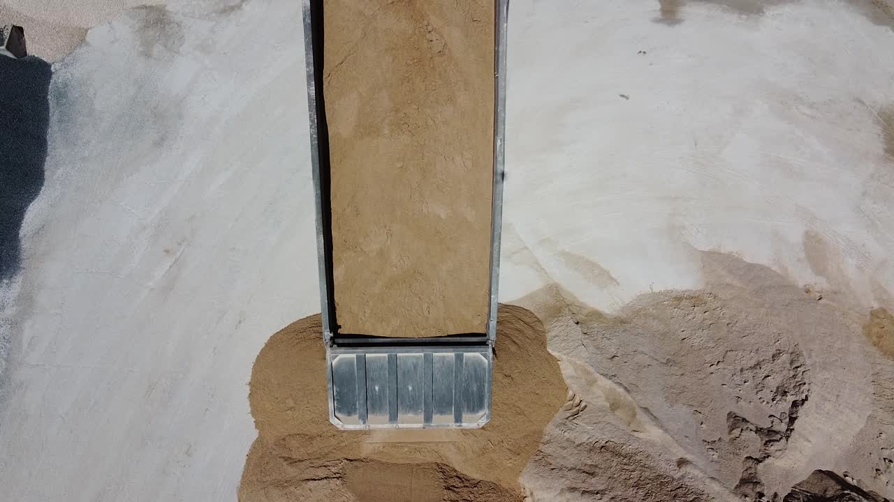 4k의 콘크리트 공장에서 천천히 모래를 내리는 덤프트럭의 공중 전망