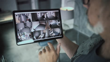 person monitoring multiple security cameras on a tablet