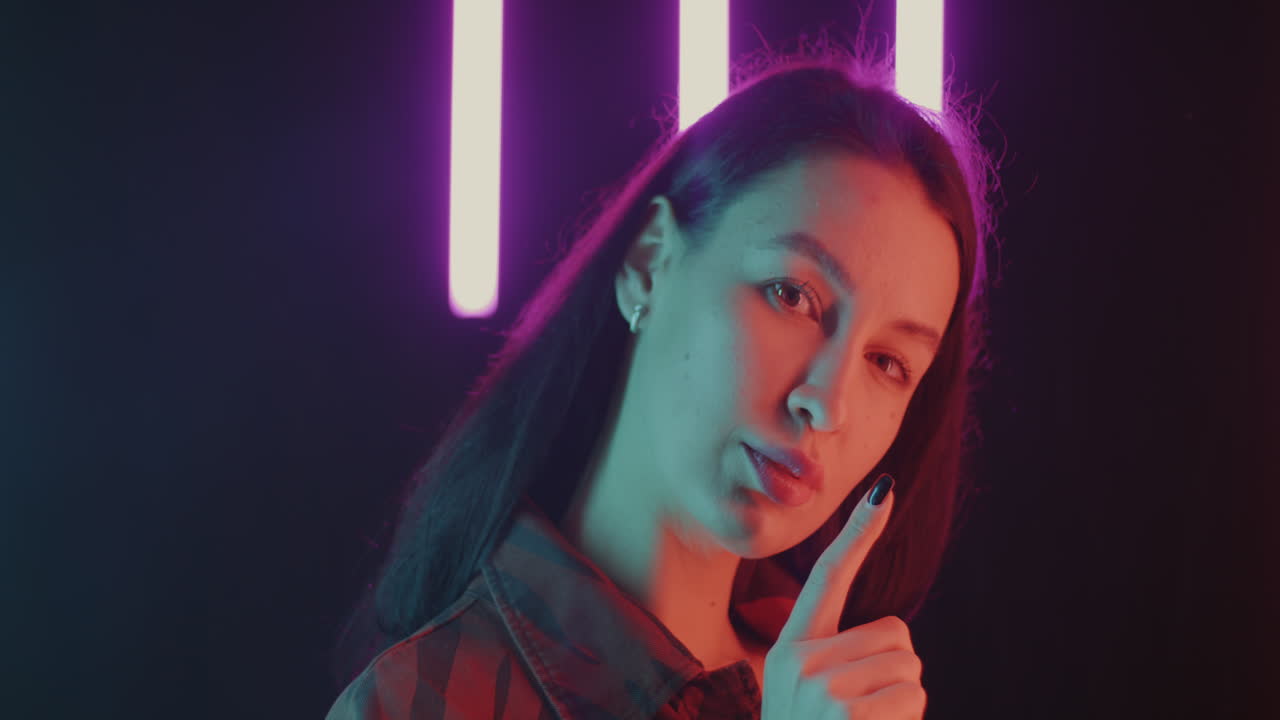 Woman in Neon Light with Finger to Lips
